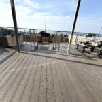 Spacious sun deck with outdoor dining, grill area, and coastal views