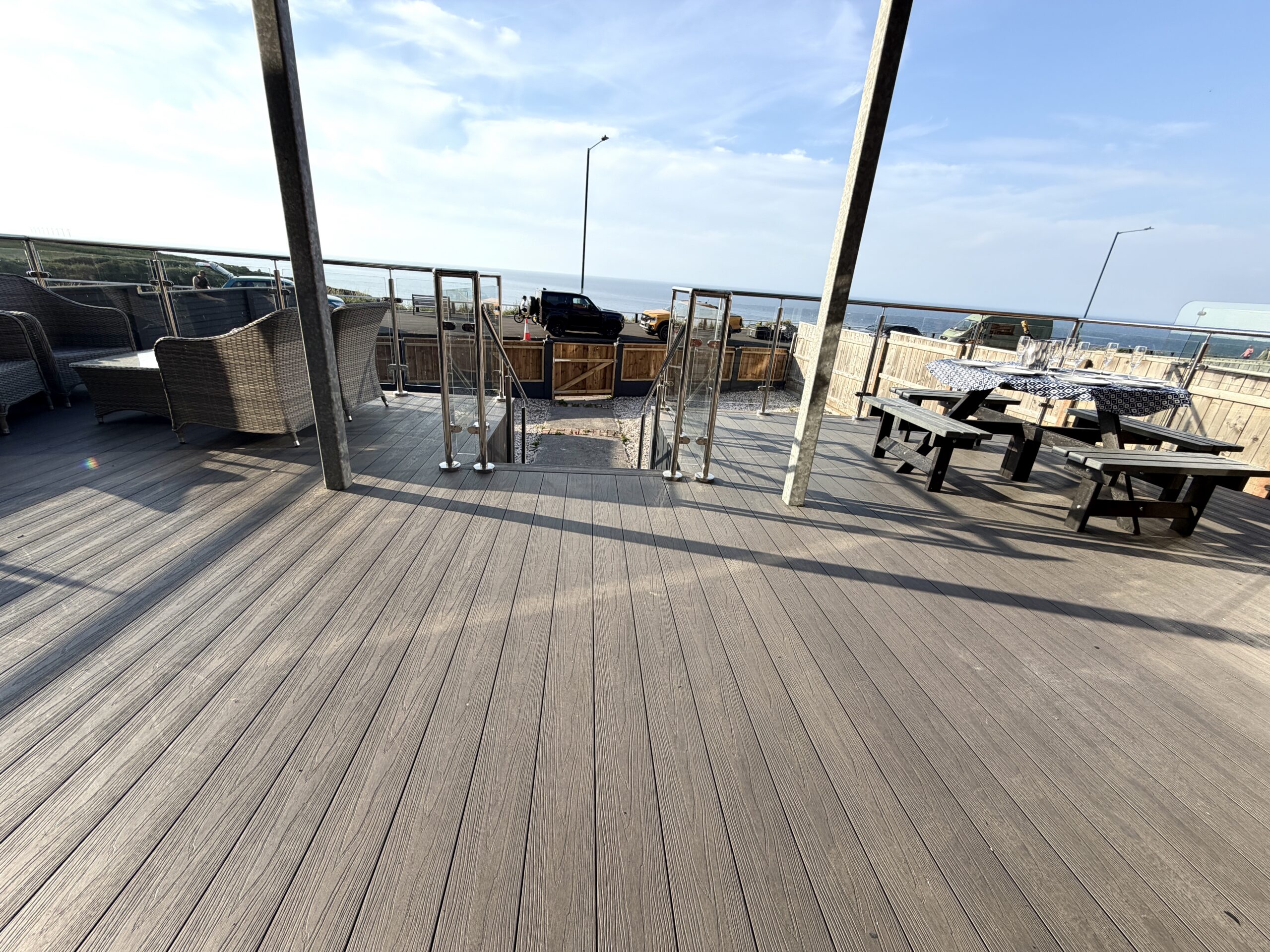 Spacious sun deck with outdoor dining, grill area, and coastal views