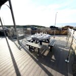 Sunny sea-view deck with outdoor dining and stylish glass railings