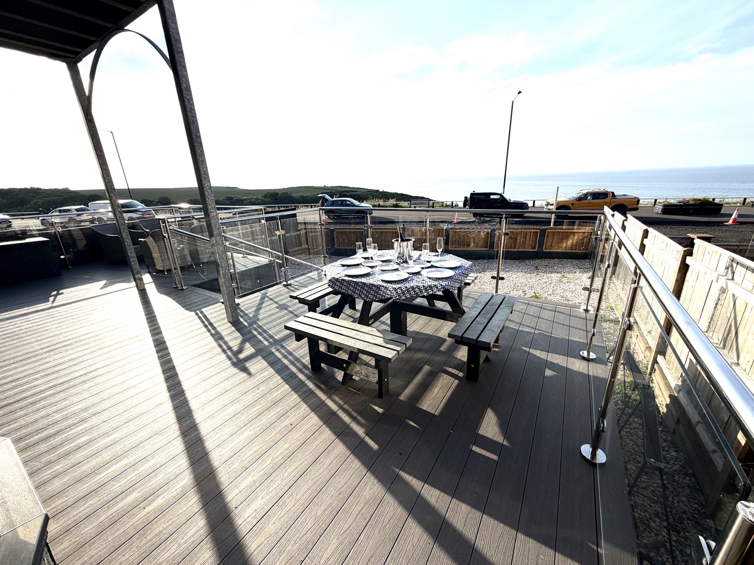 Sunny sea-view deck with outdoor dining and stylish glass railings