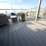 Spacious sunlit deck with comfy seating and partial sea views