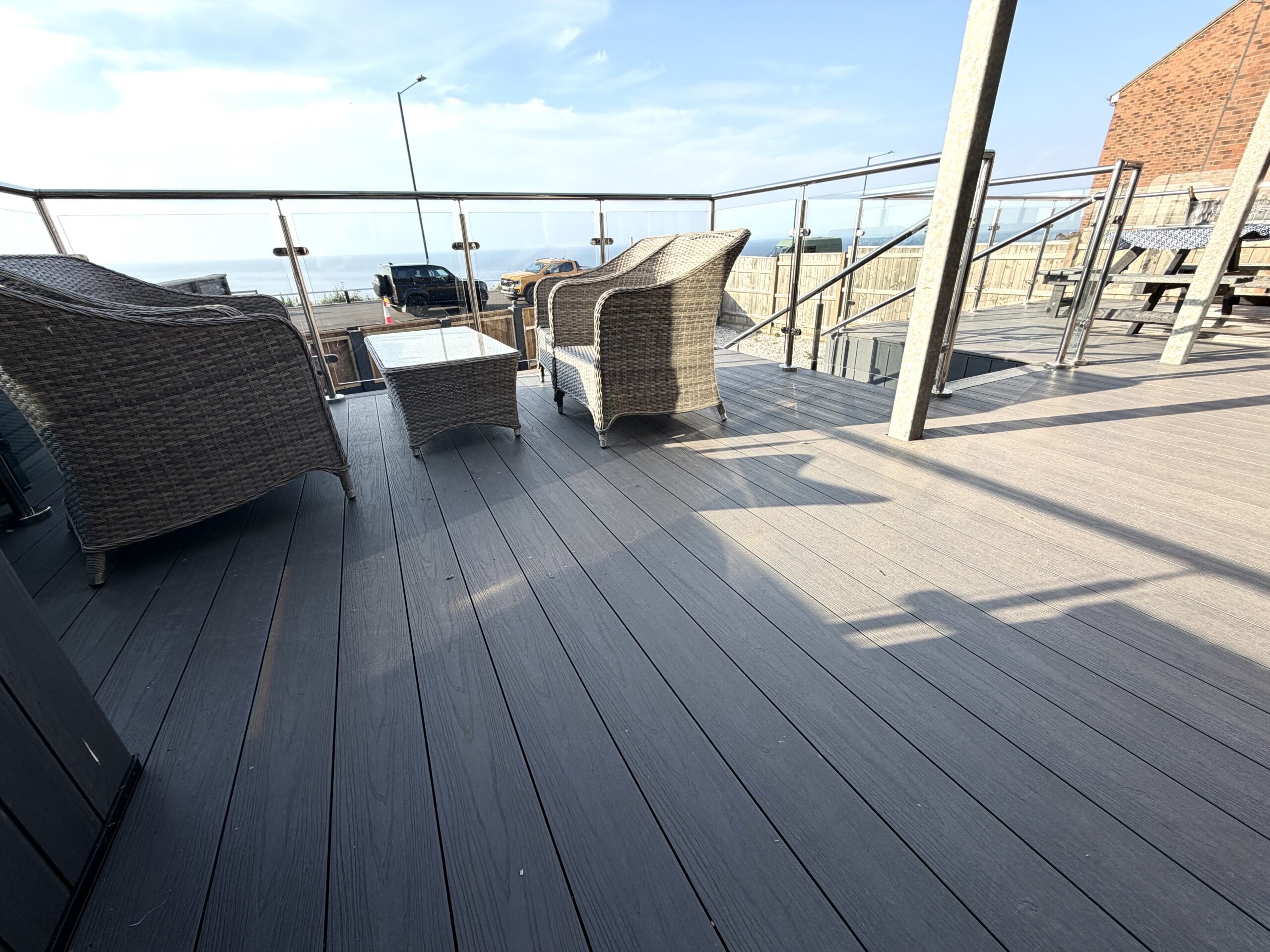 Spacious sunlit deck with comfy seating and partial sea views